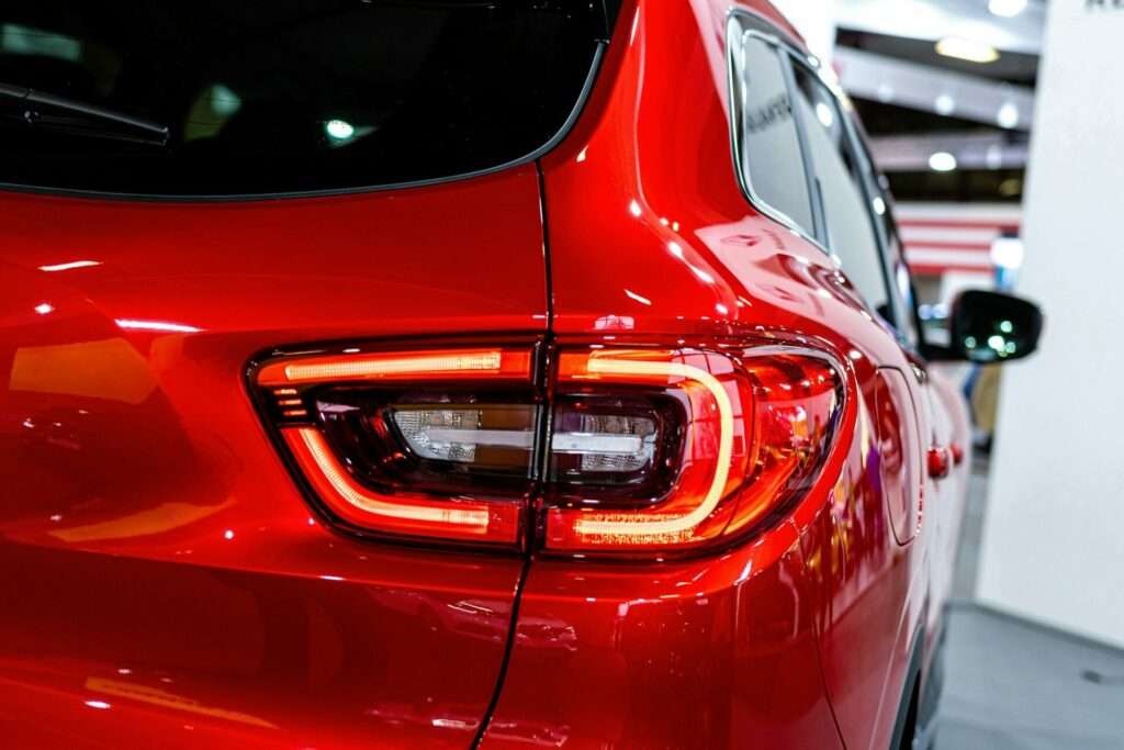 Mein Autofotograf: Wie ich meine Fahrzeugfotos verbessere 7 Fotograf Hannover Nahaufnahme des Rücklichts eines roten Autos, präsentiert von einem Autofotografen. Das Bild fängt das elegante Design und die leuchtend rote Beleuchtung ein und konzentriert sich auf die Details und Konturen des Rücklichts und der angrenzenden Karosserie in einem gut beleuchteten Innenraum. Fotograf in der Nähe.